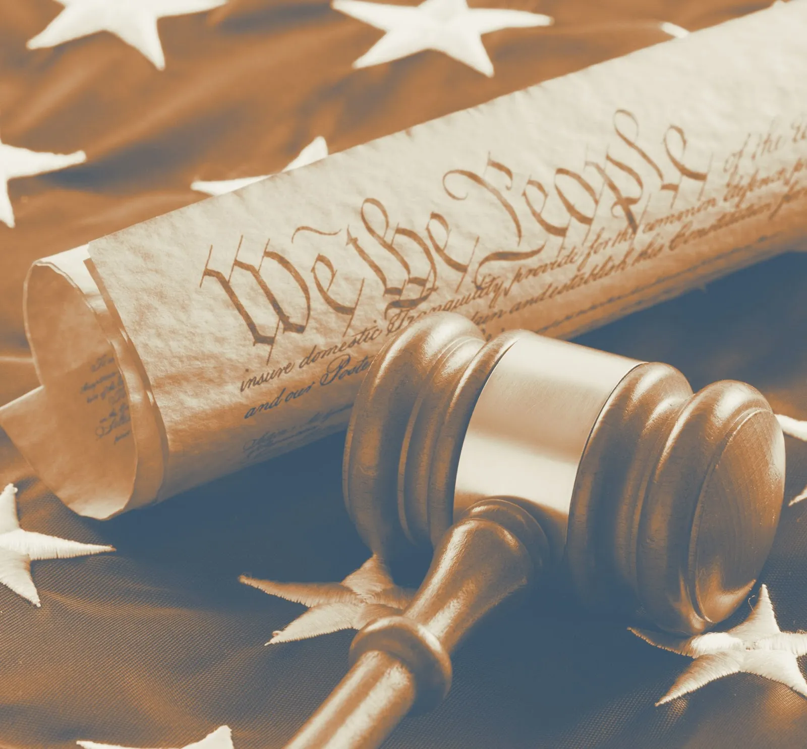 Rolled U.S. Constitution with We the People text and wooden gavel on American flag
