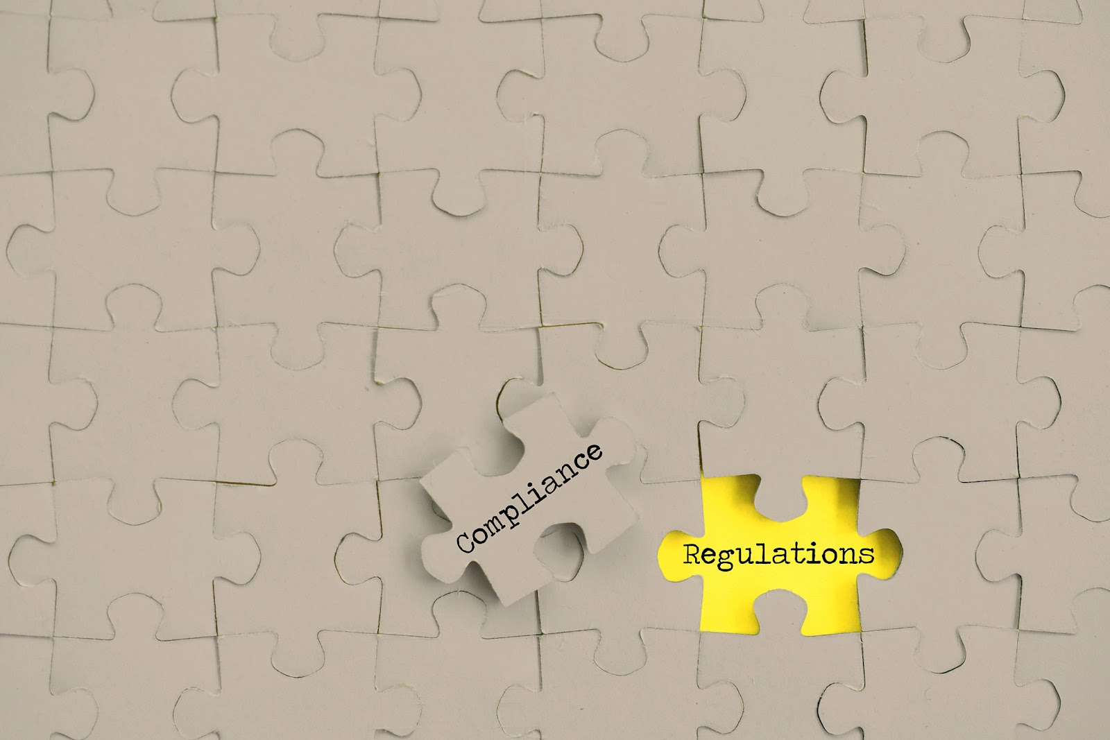 Puzzle with compliance piece removed revealing yellow regulations piece underneath