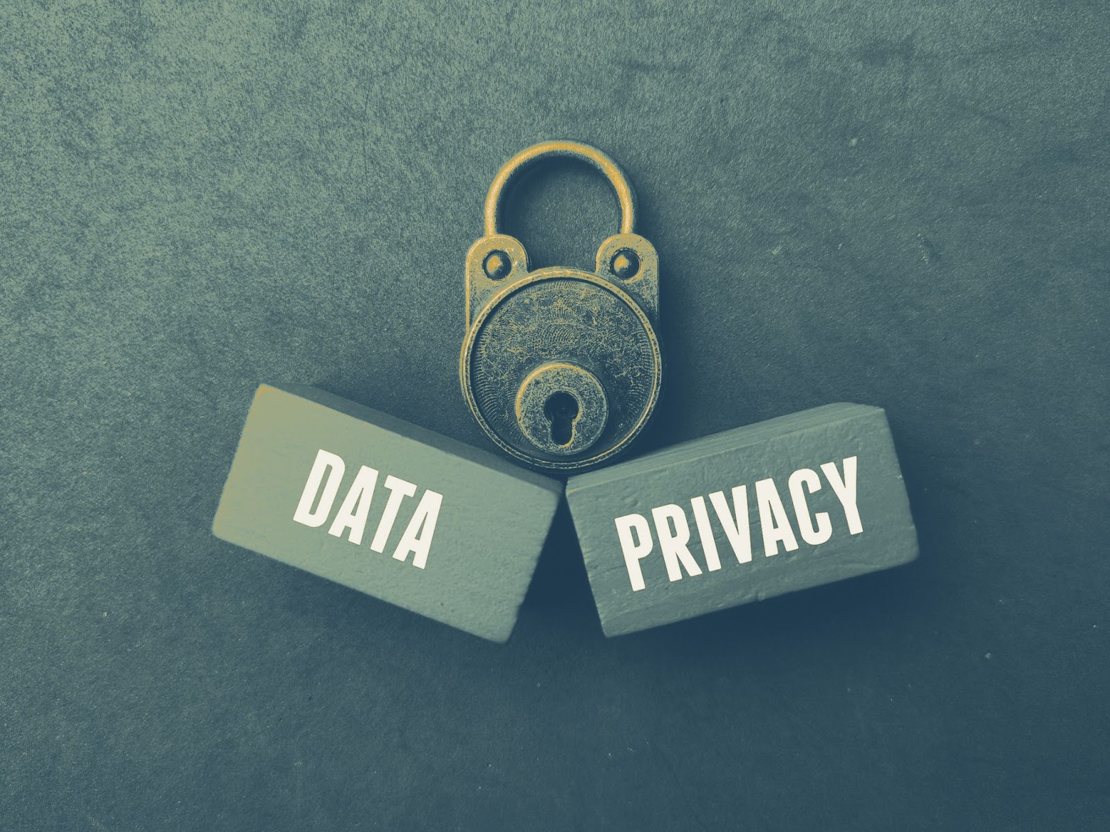 Vintage brass padlock resting on two dark wooden blocks reading Data and Privacy