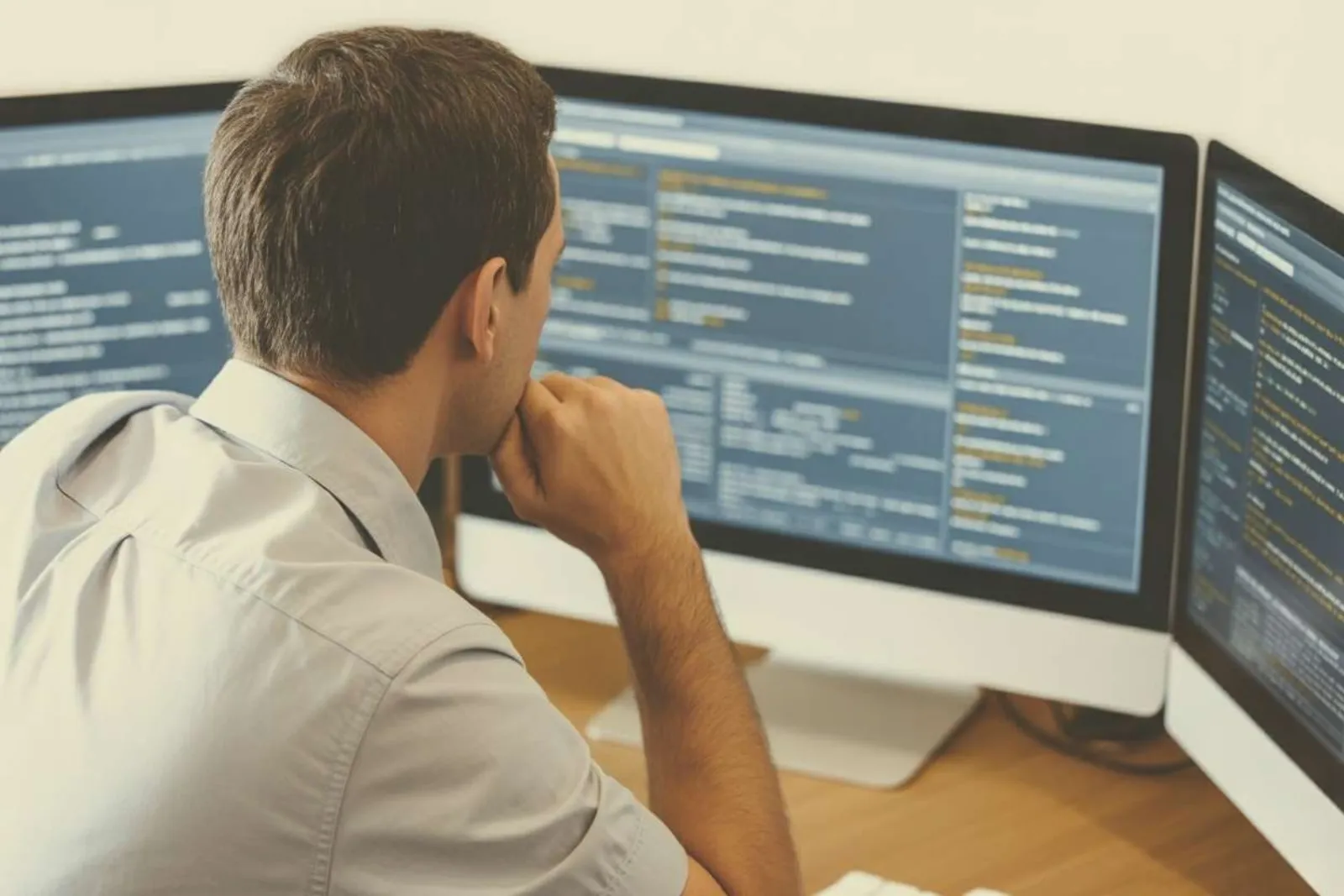 Professional analyzing data on multiple computer monitors at a desk
